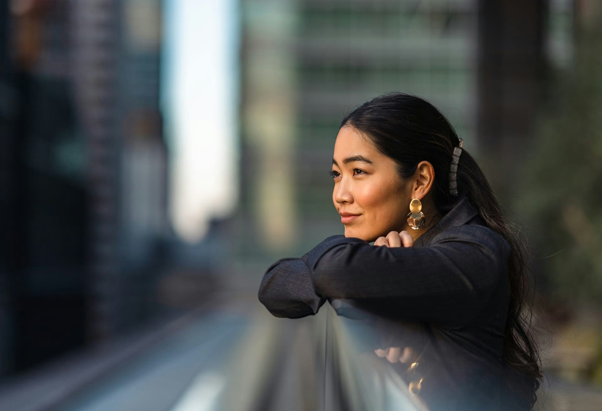 Woman resting her arms on a city balcony