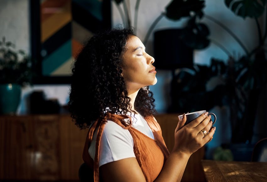 Woman closing her eyes while holding a cup