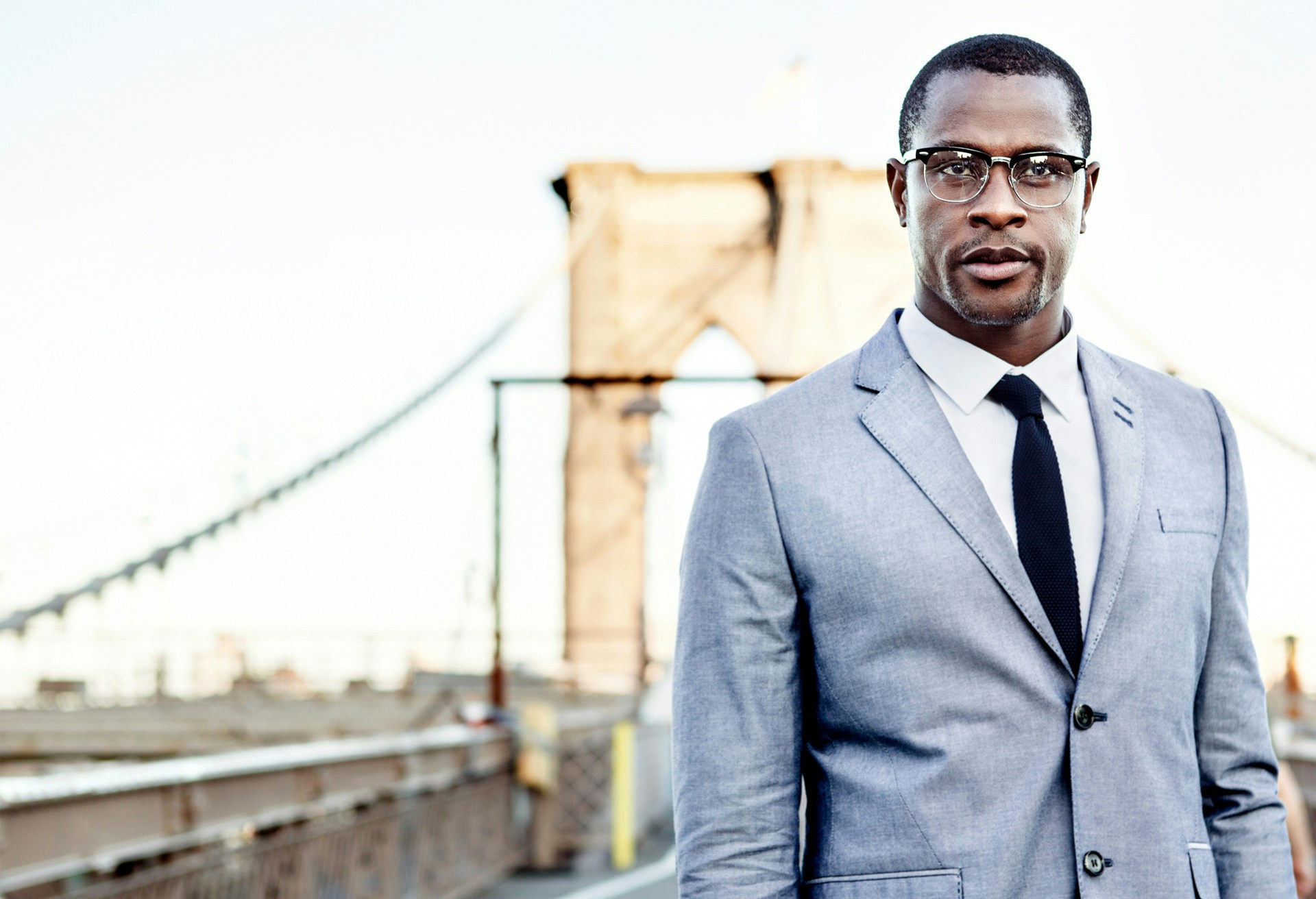 Man in a light grey suit wearing glasses