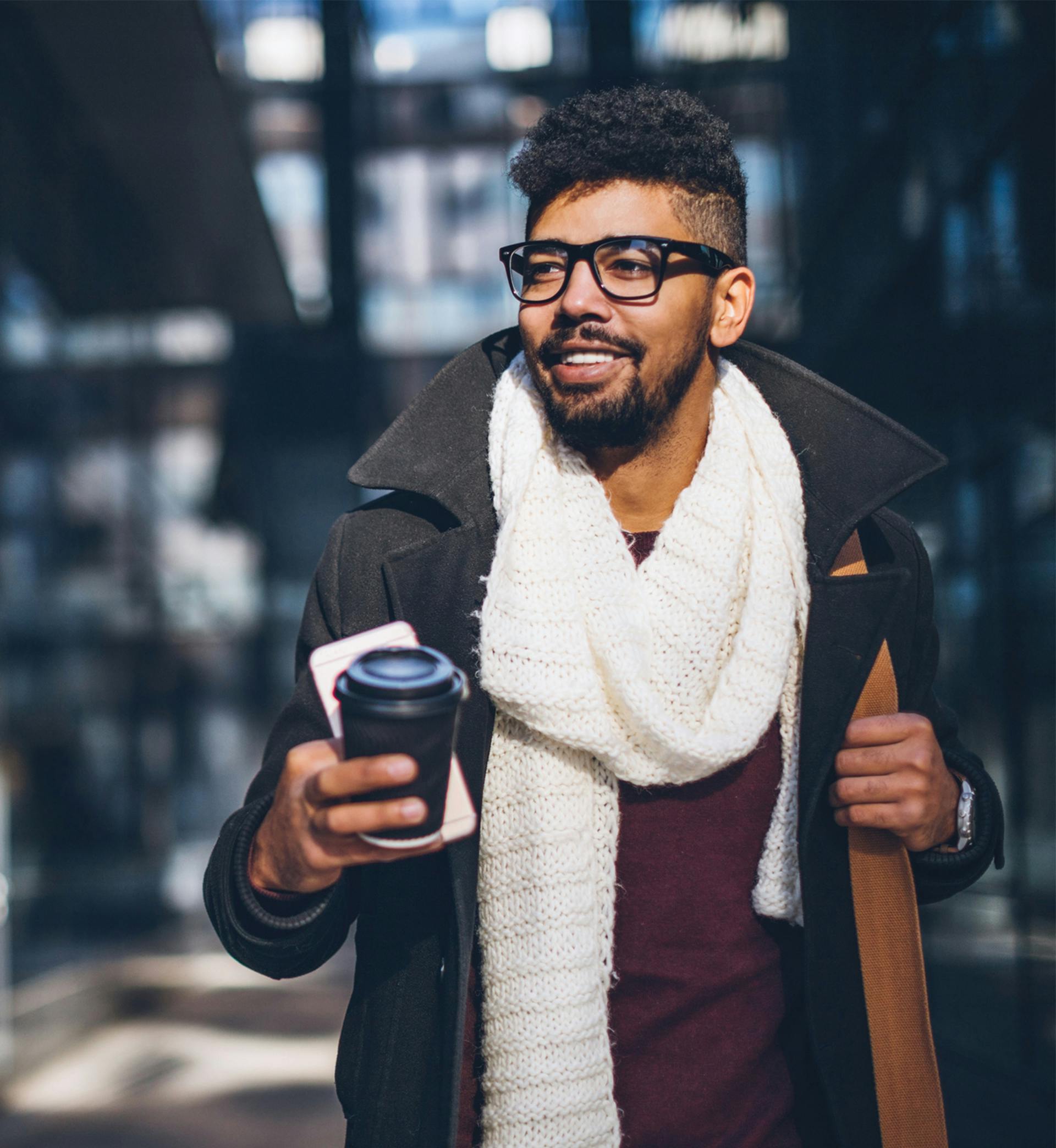 Man holding cell phone and coffee walking to work