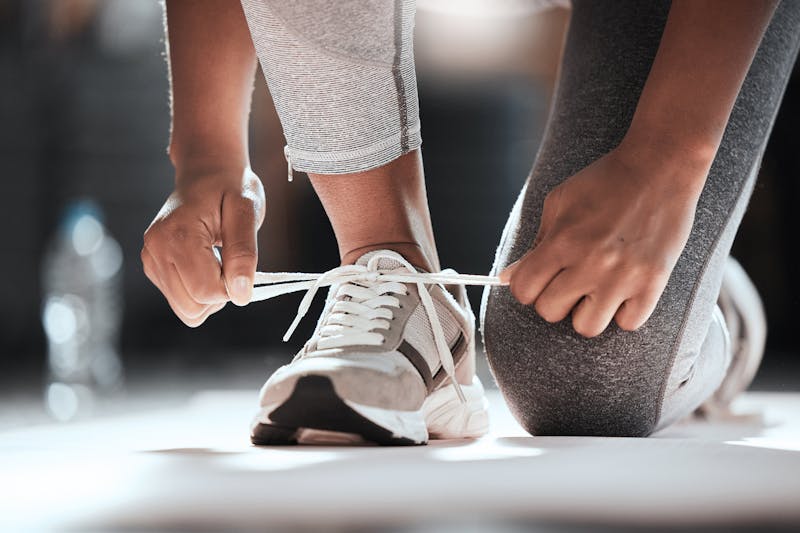 Woman kneeling and tying her shoe