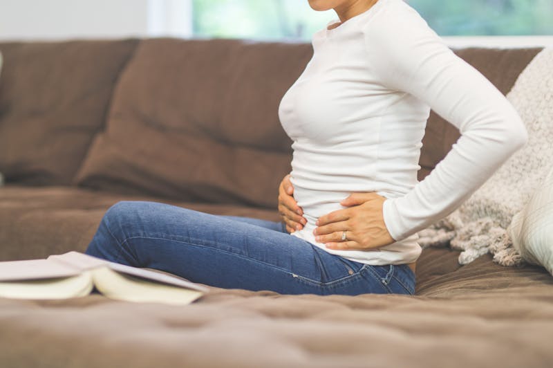 Woman on couch holding her pelvic area