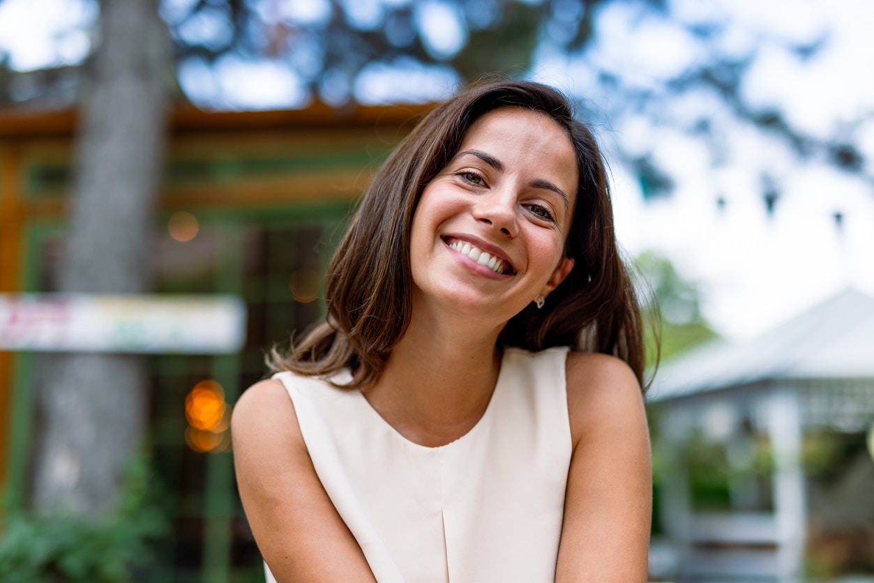 A woman in a white blouse outside smiling