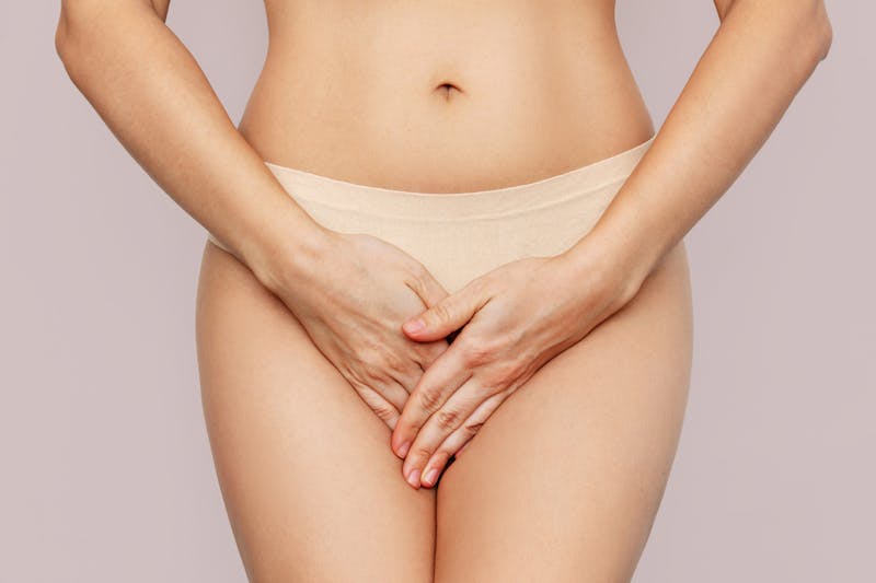 Woman's pelvic area shown with her in underwear with hands cupped to show discomfort