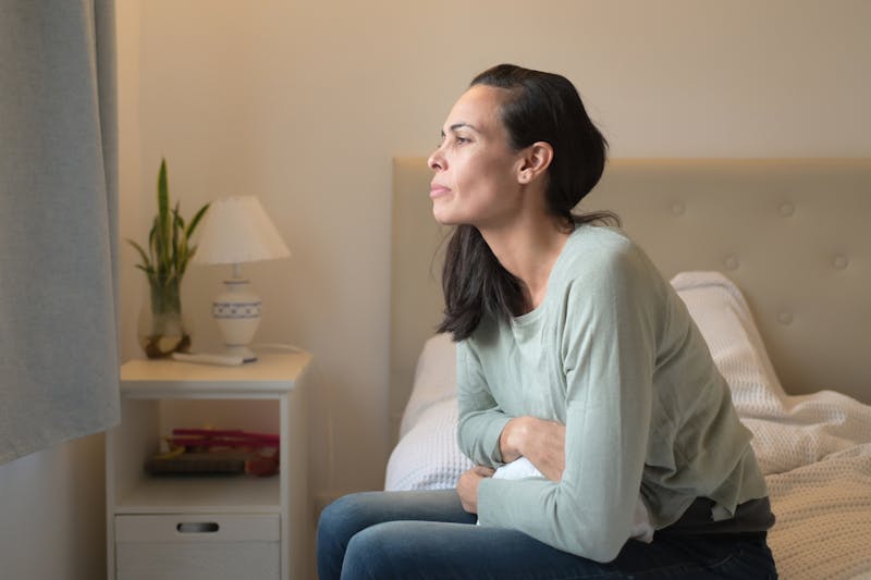 Woman in Fibroid pain sitting on edge of bed