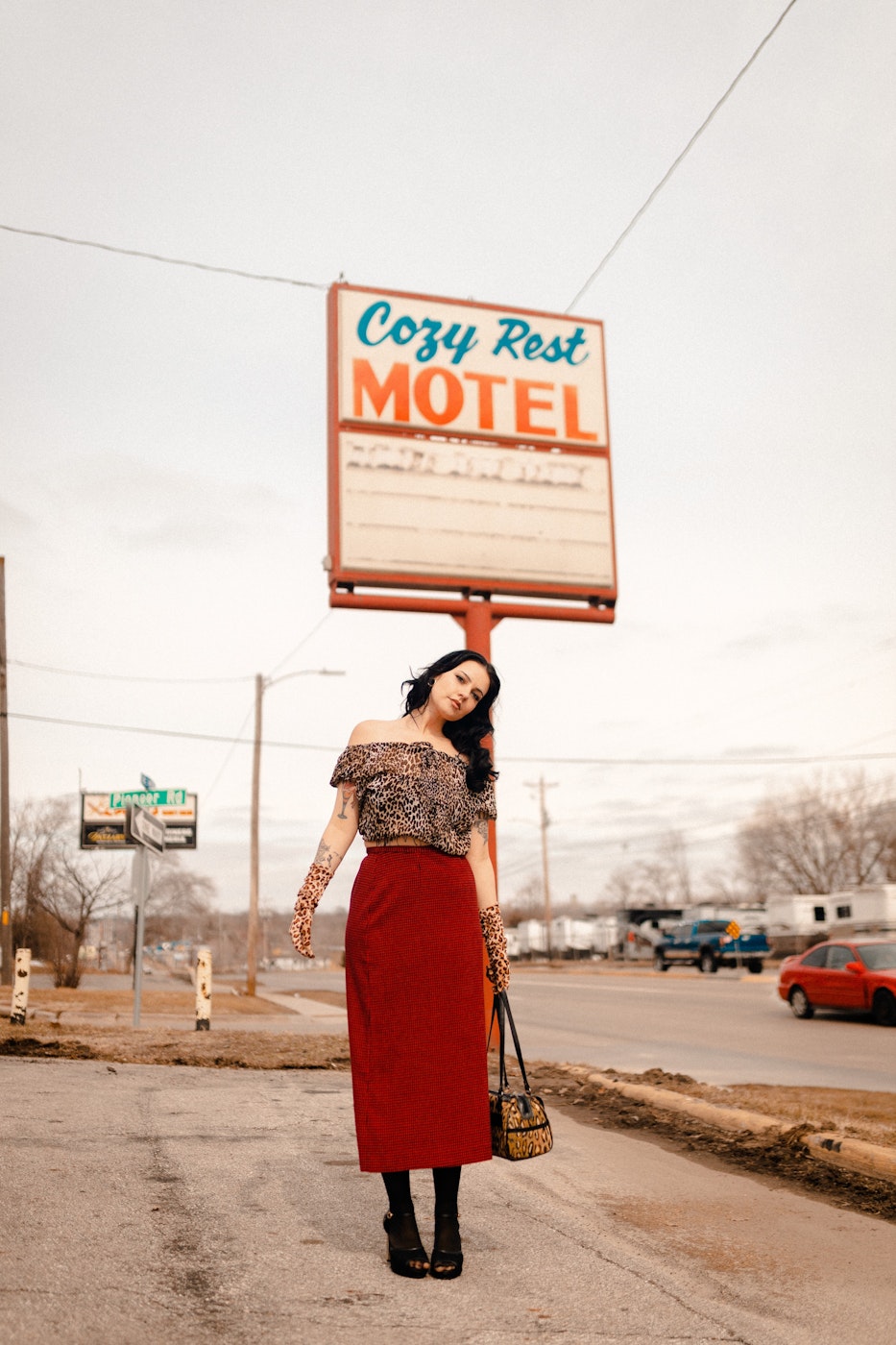 a woman in a red skirt holding up a motel sign