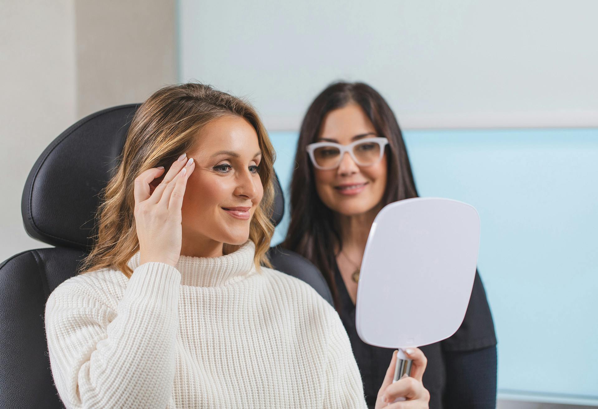 Two women looking in a mirror