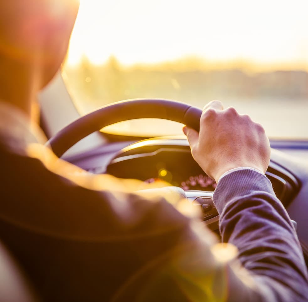 Man driving a car at sunset
