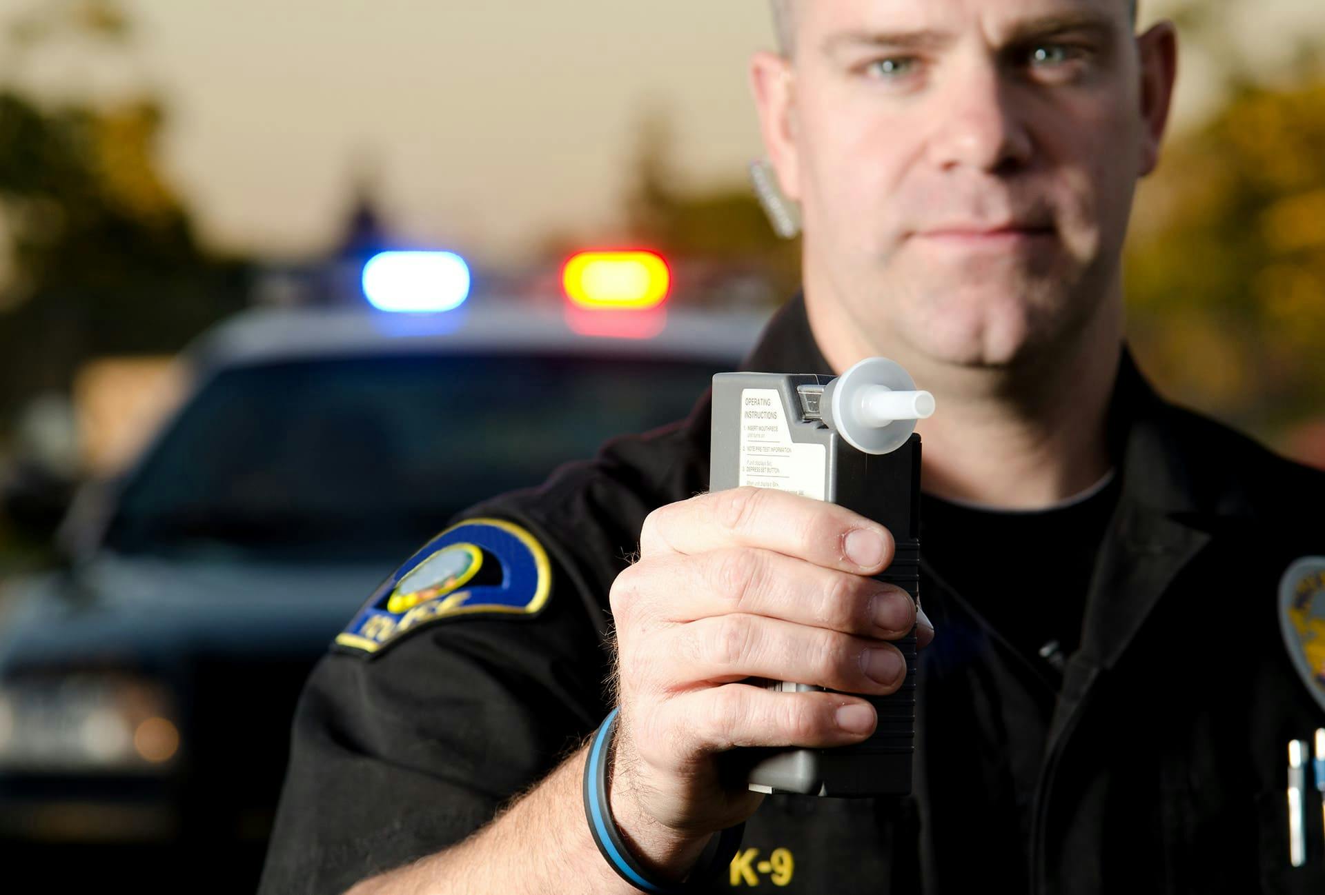 Officer holding up a breathalyzer to a person