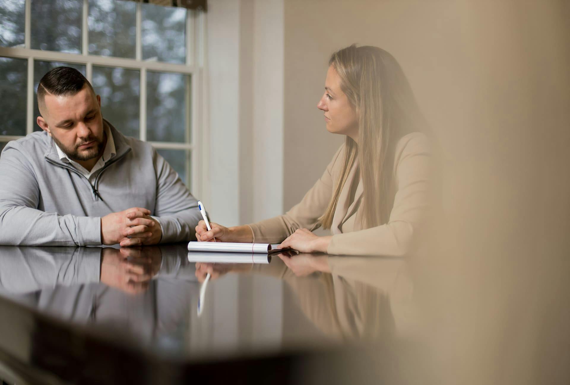 Woman speaking with a man and taking notess