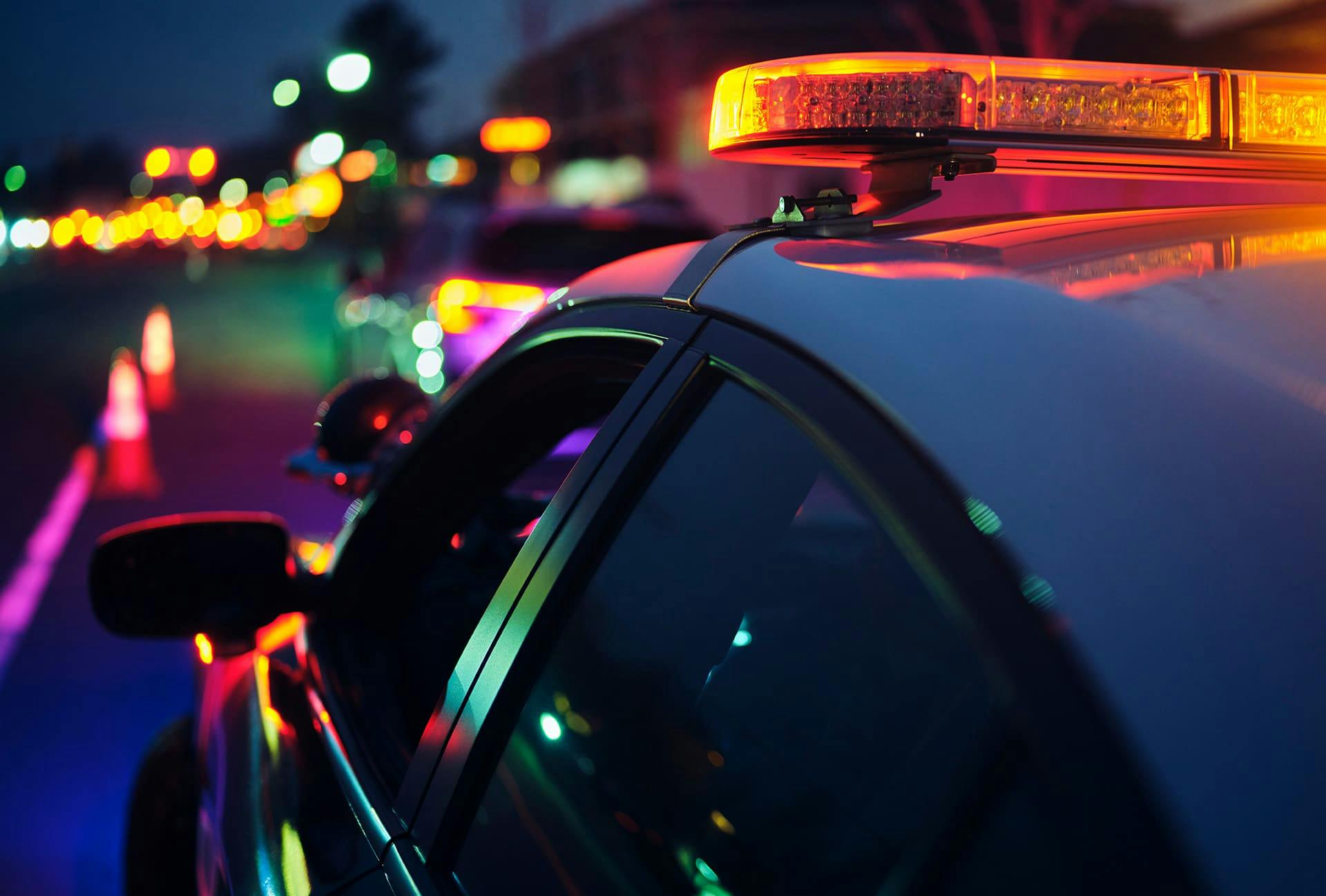 Cop car with sirens on behind another car