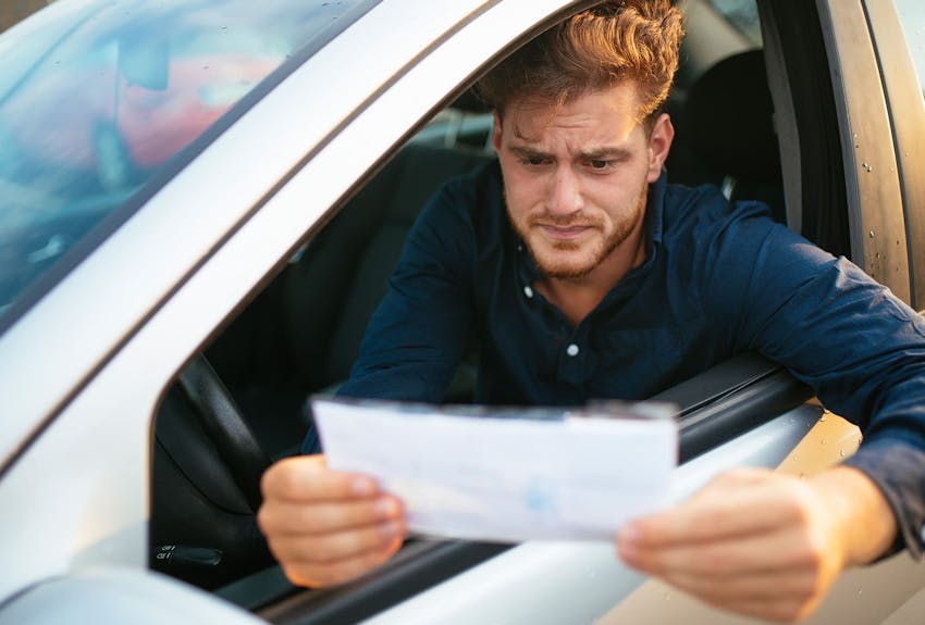Man reading something on the side of the road in his car