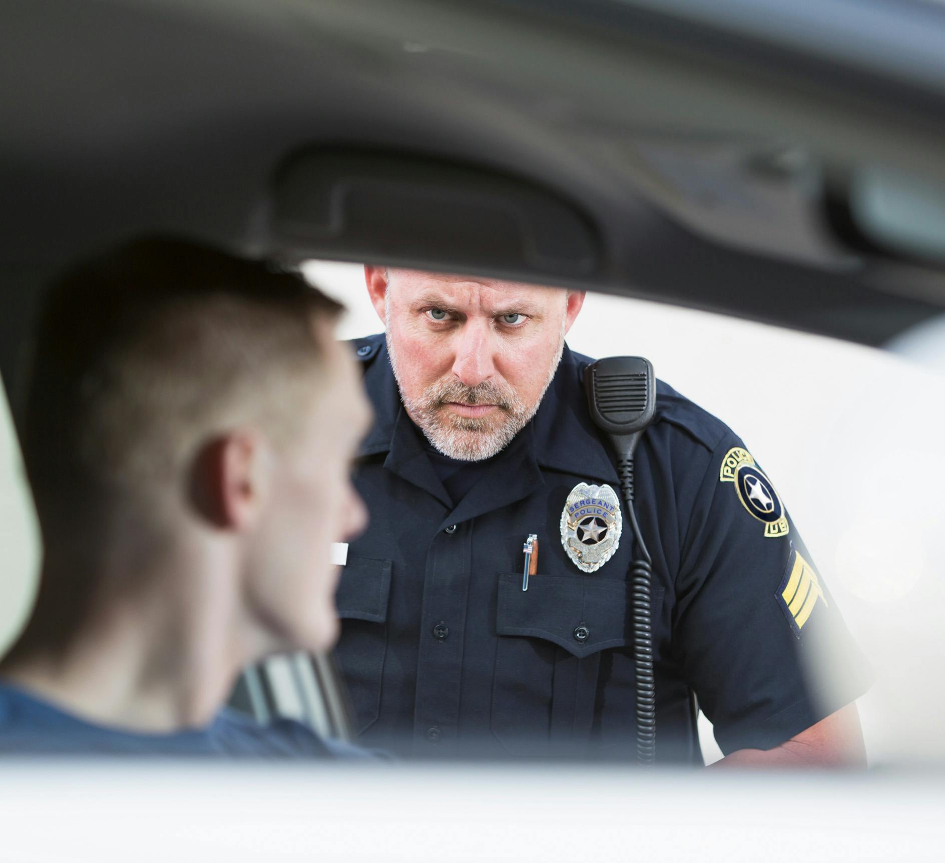 Police officer looking at a person from outside the car.