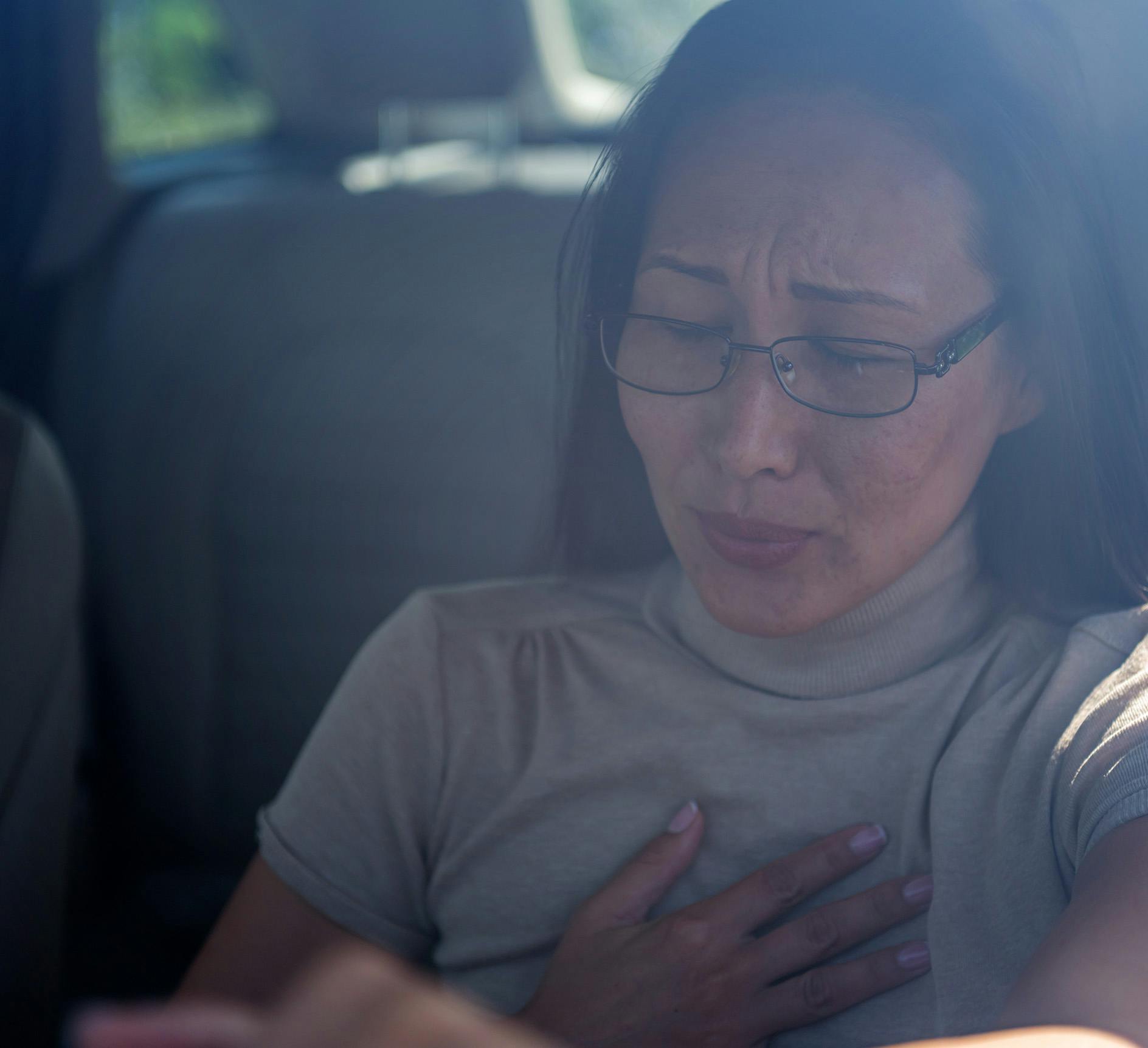 Woman holding her chest while driving