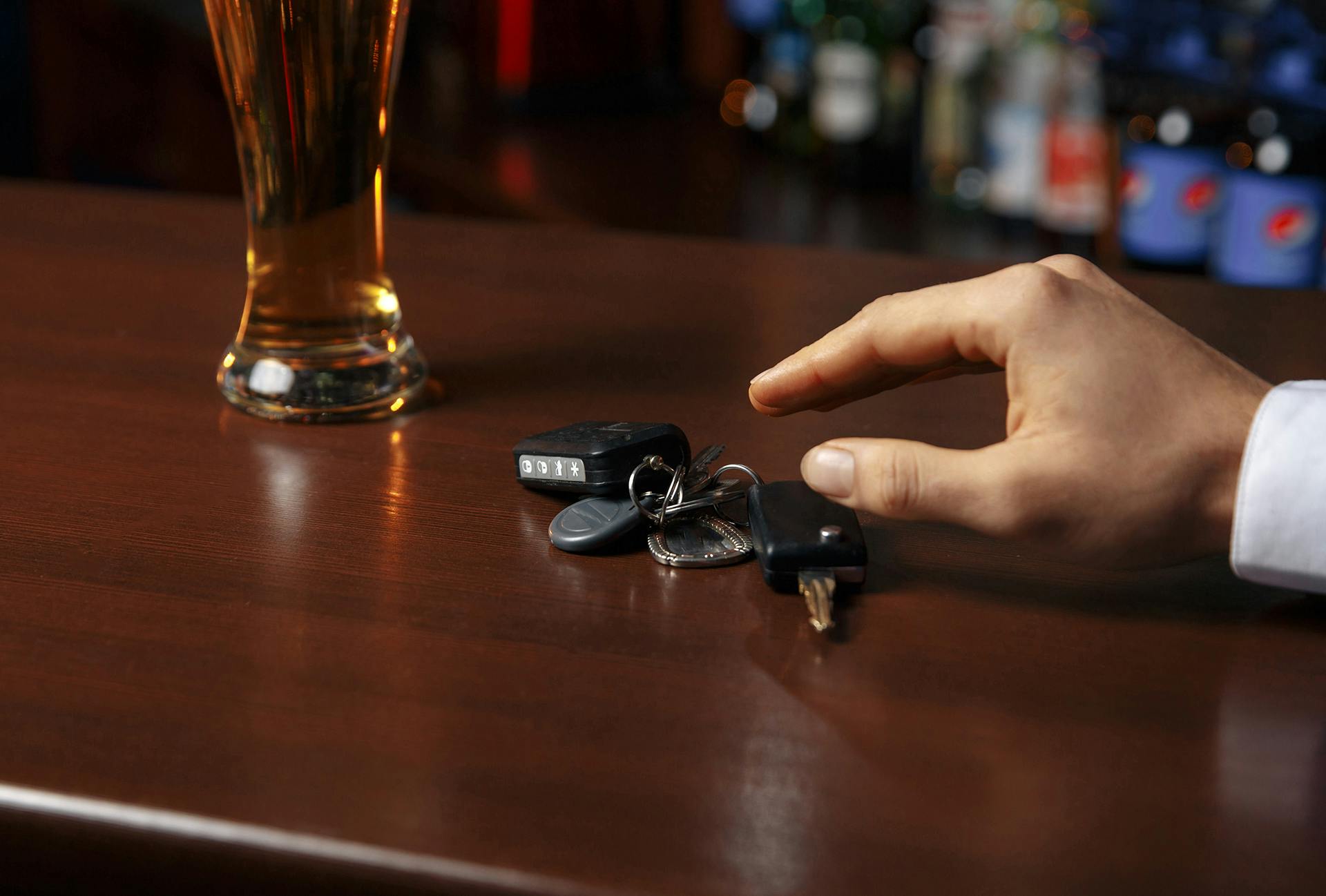 Person reaching for keys next to alcoholic beverage
