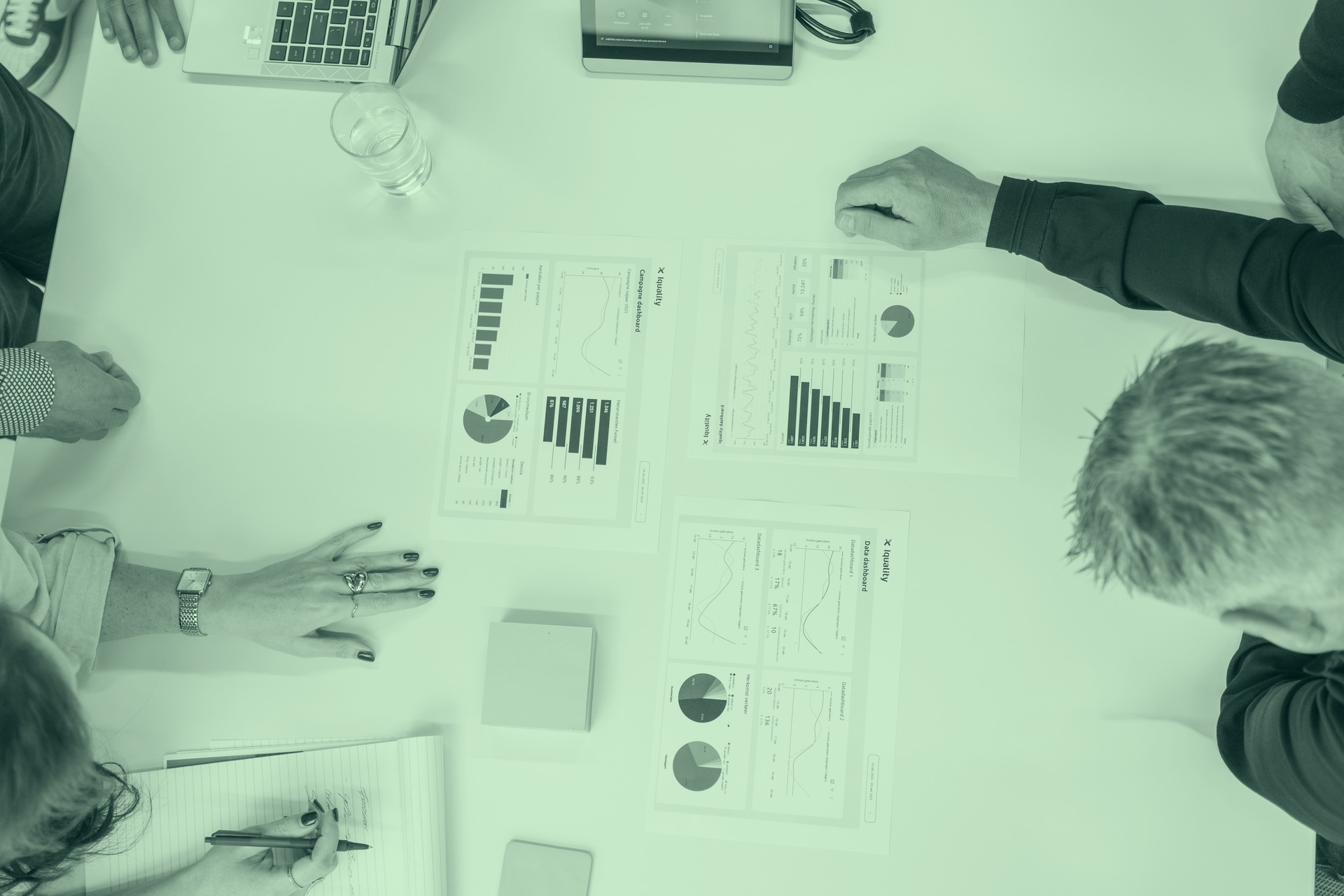 Bovenaanzicht van Iquality data-dashboards en rapportages op vergadertafel