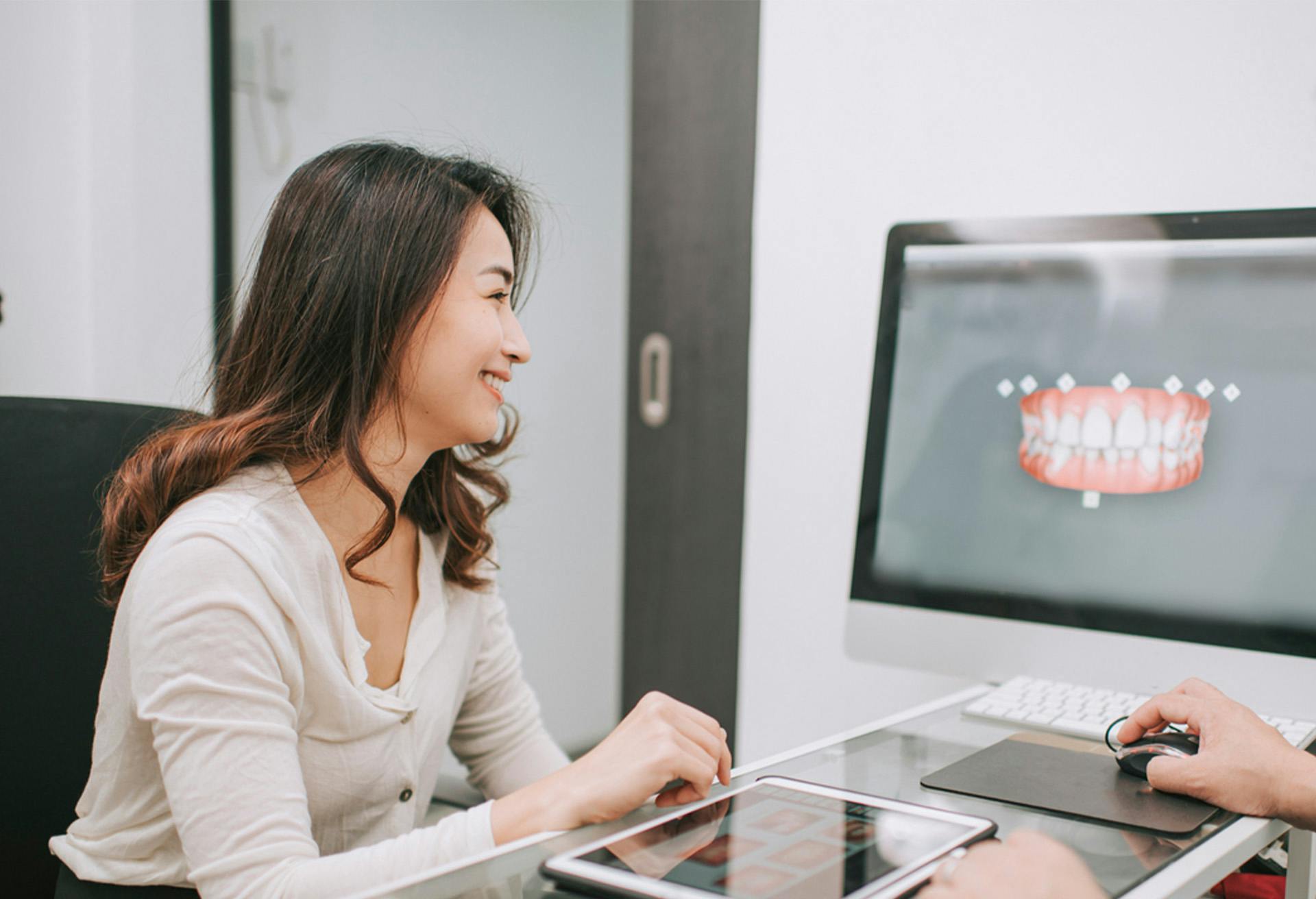 there is a woman sitting at a desk with a computer and a man