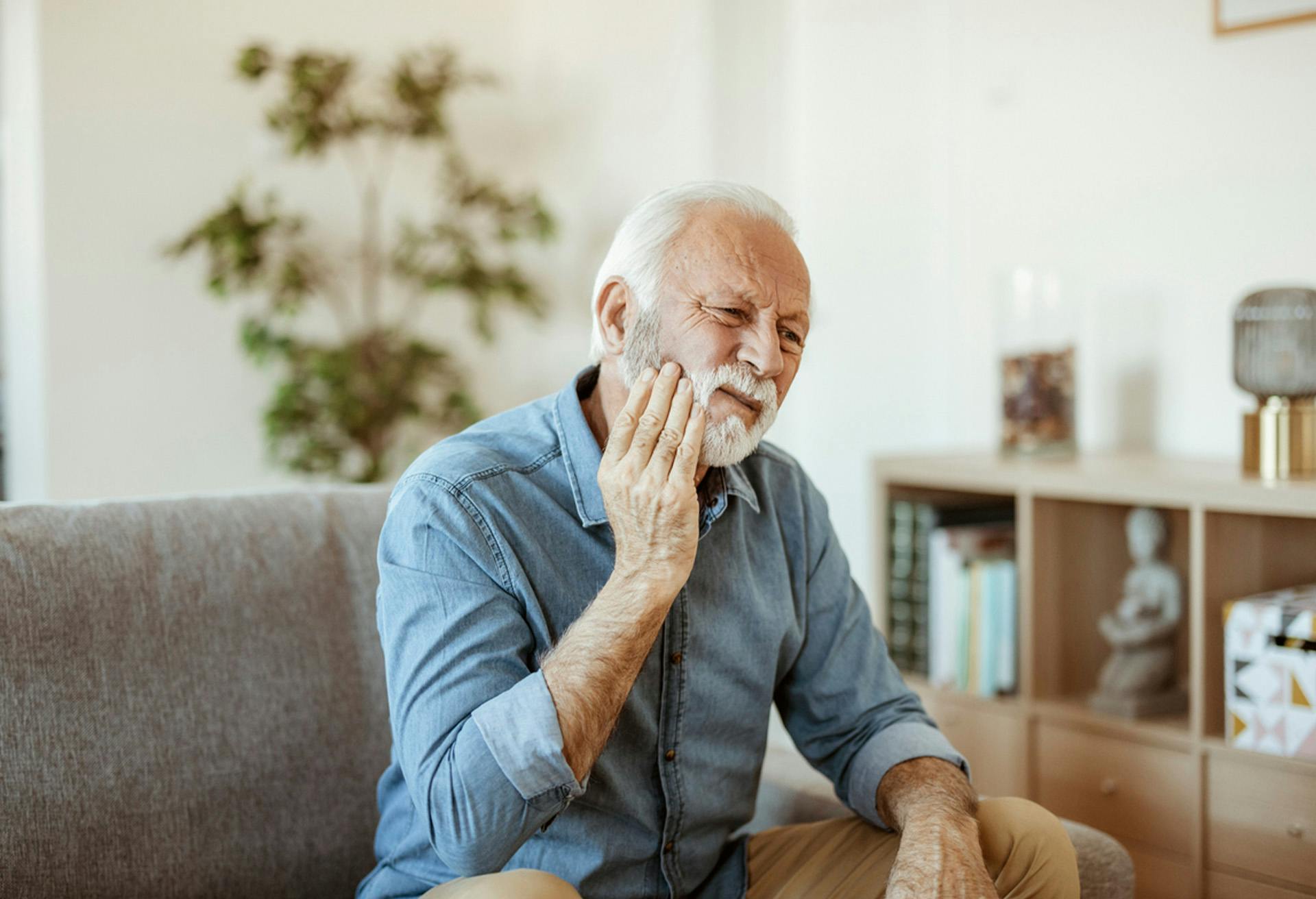 older man sitting on a couch with his hand on his chin
