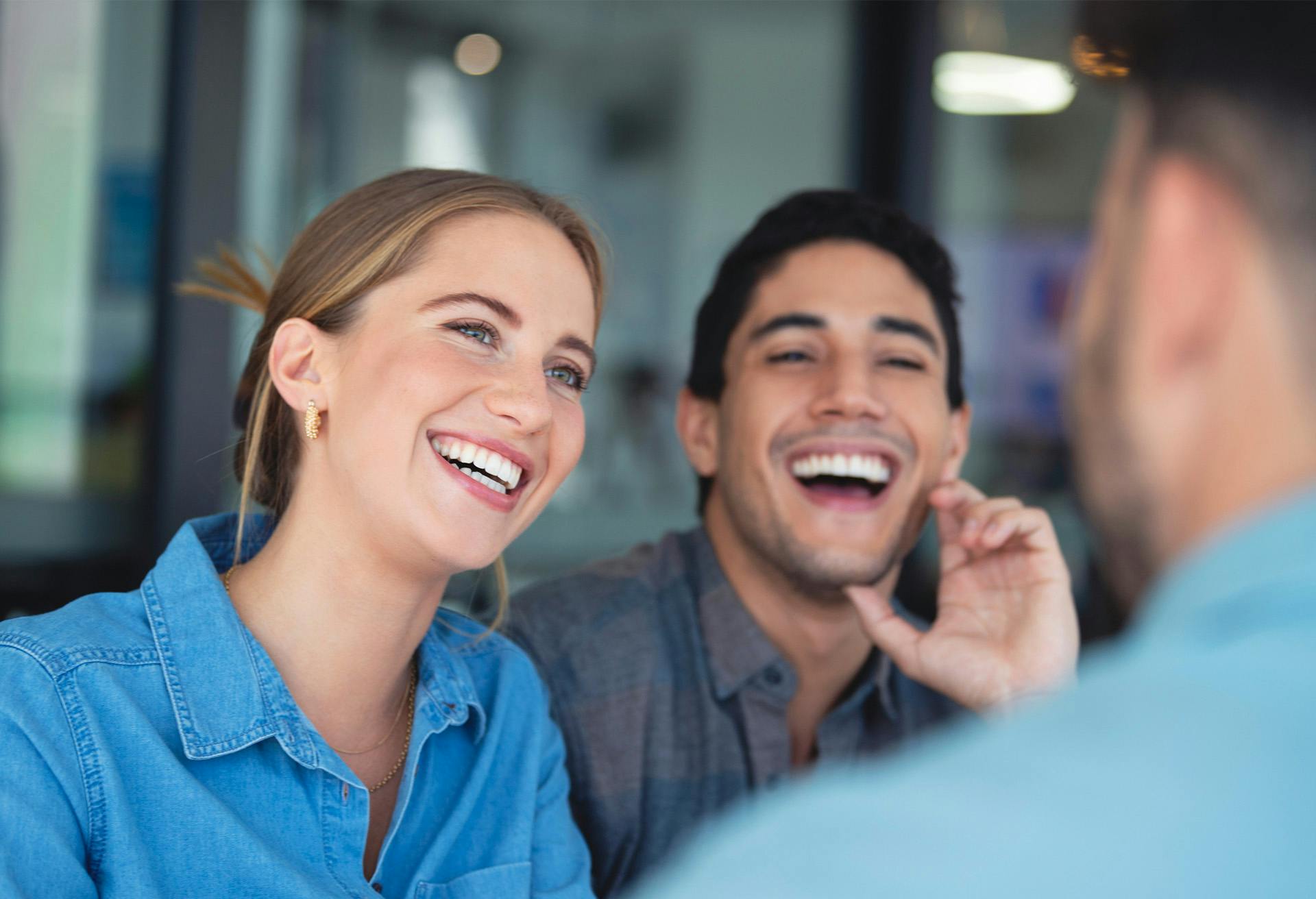 smiling woman talking on cell phone while man laughs with another man