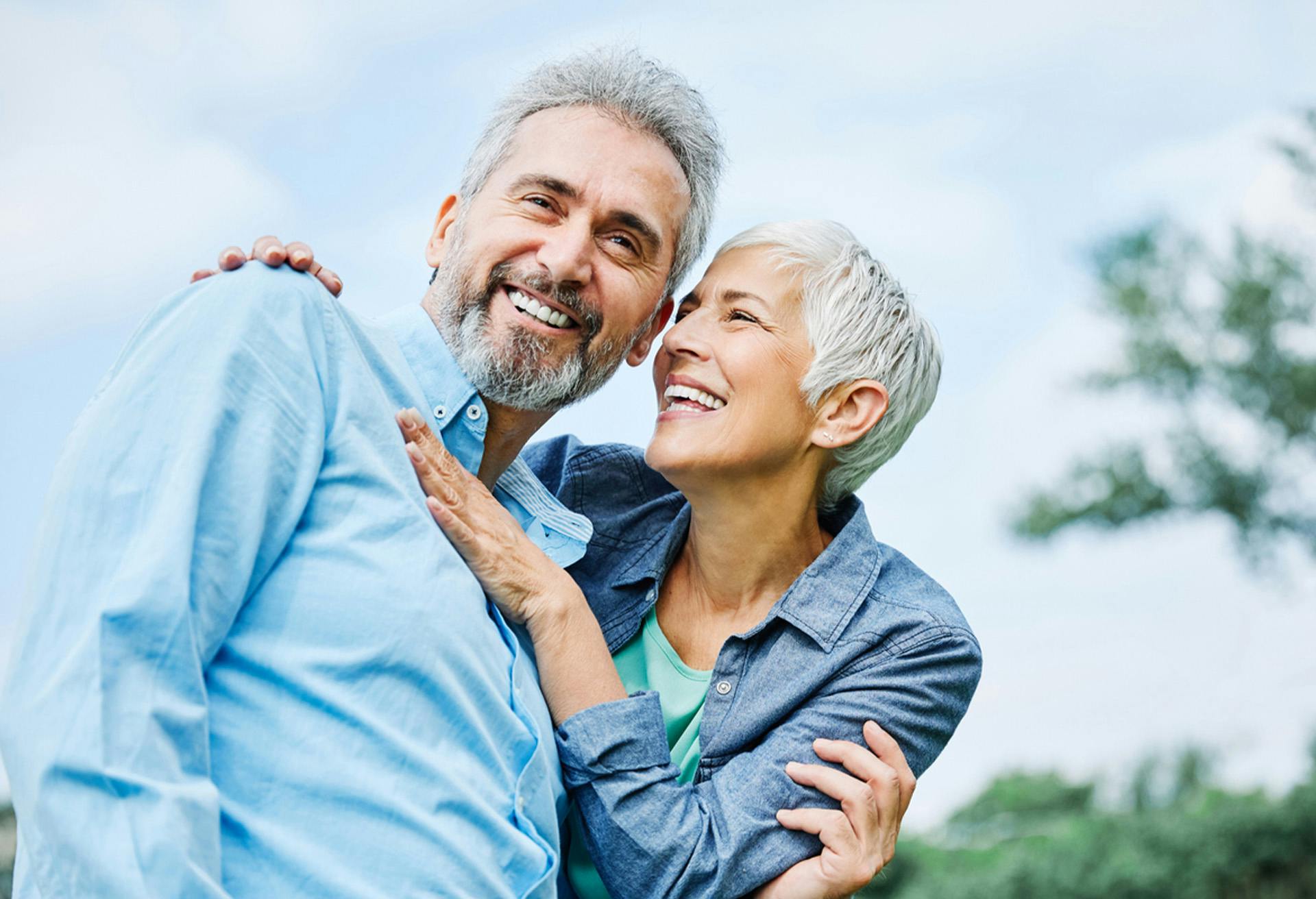 smiling older couple embracing each other in a park