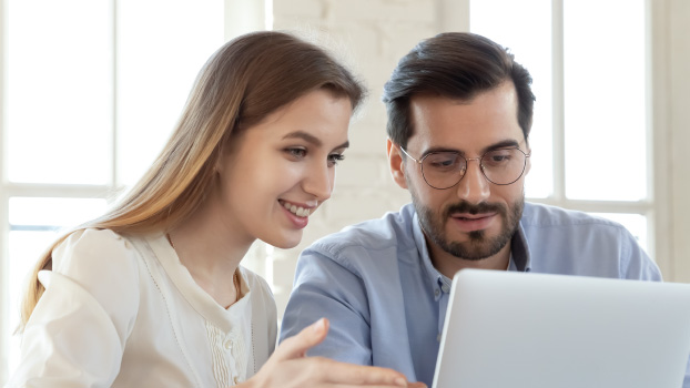 A woman showing a new male employee how to log in to the data system