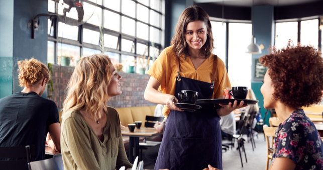 A female waitress serving two female customers in a cafe