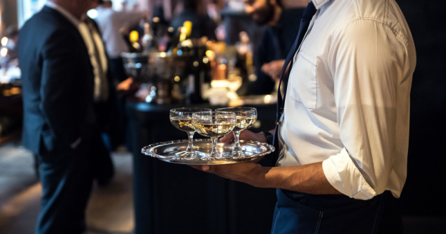 A waiter at an event serving cocktails in a silver tray