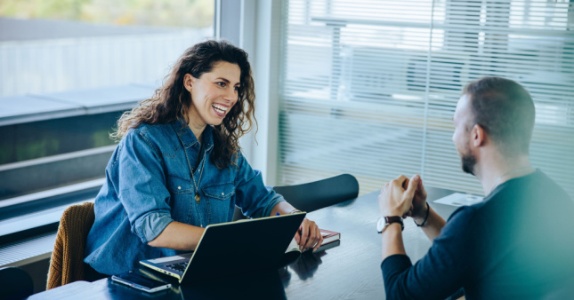 A woman HR manager smiling while interviewing a male job candidate