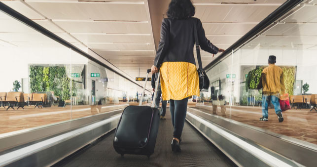 A woman with luggage walking through an airport