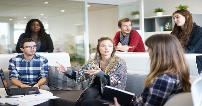 New male and female employees sitting in a meeting room undertaking induction.