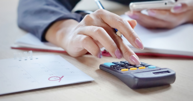 A woman using a calculator to work out the correct rate of pay