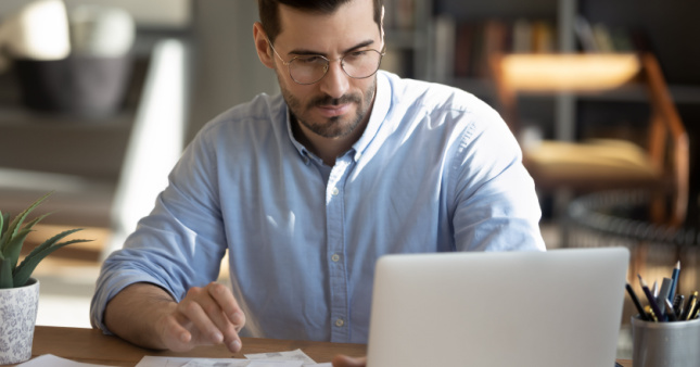 A man at a desk with a laptop working on claculations