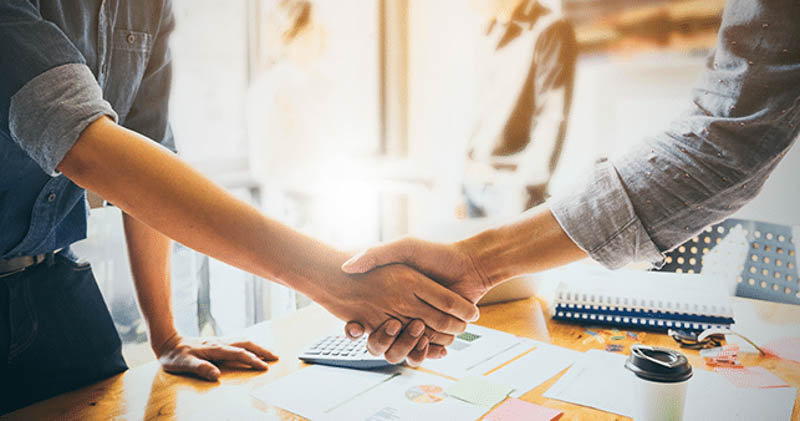 Two young office workers shaking hands in agreement