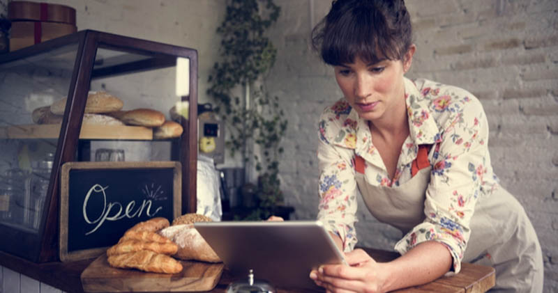 female bakery owner in floral shirt using tablet