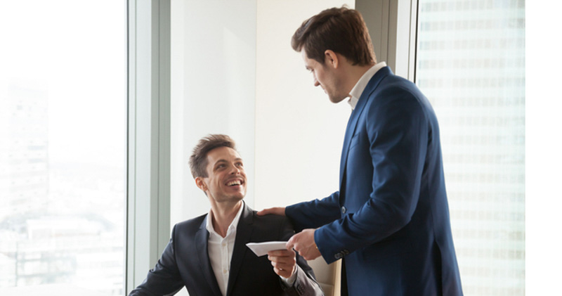 2 male business associates in board room with pay slip