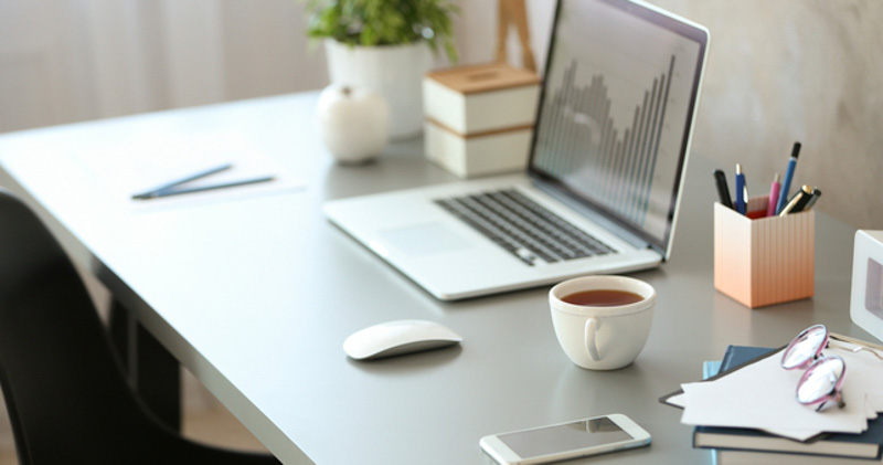 empty workstation with laptop and cup of tea