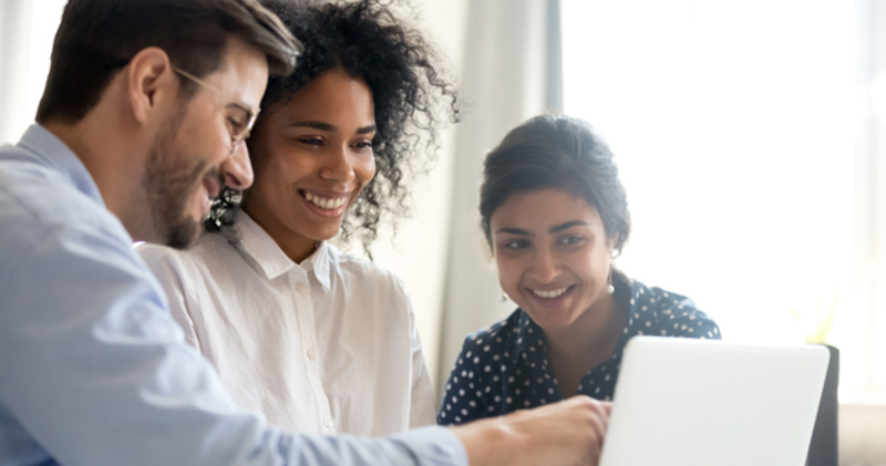 3 happy corporate employees looking at laptop