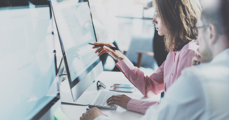 female office worker points out detail on computer screen