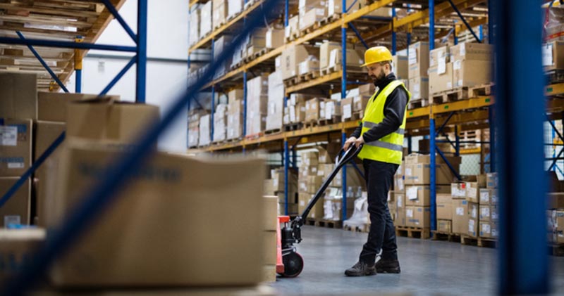 Warehouse worker lifts up boxes with a small forklift