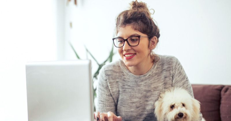 happy female remote worker reads emails with dog