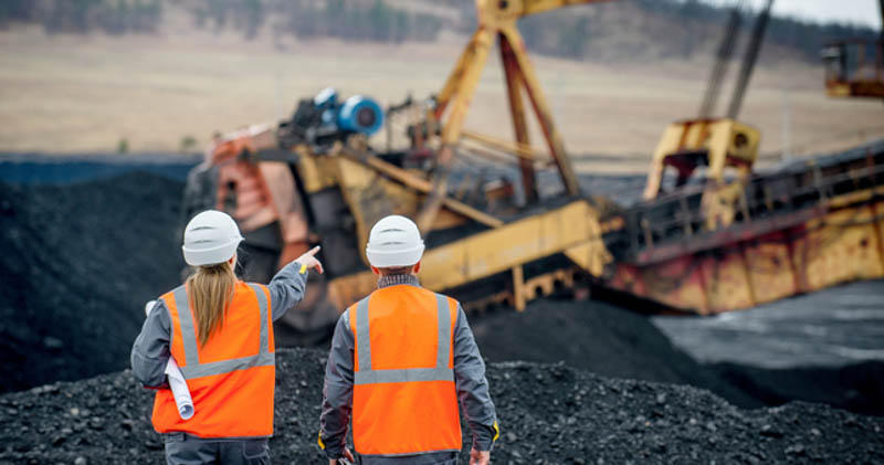 2 miners stand in mine in high vis