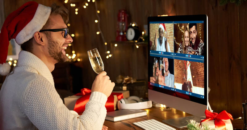 cheerful remote worker in santa hat sips champagne during virtual christmas party