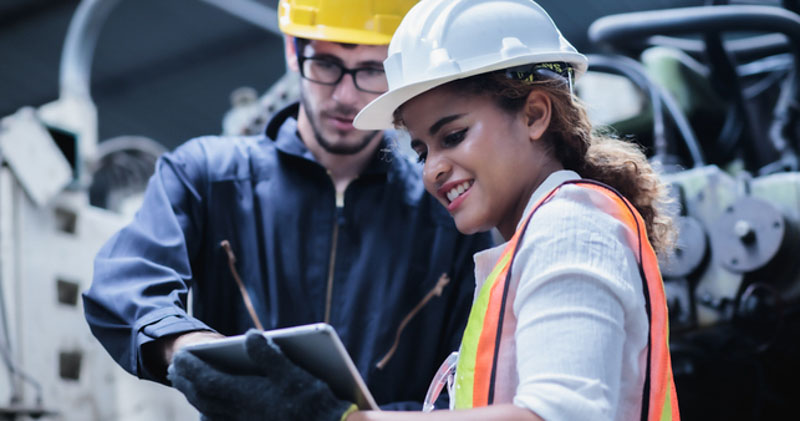 cheerful female construction worker with male coworker in workshop