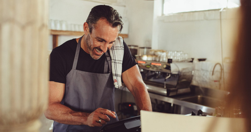 happy male barista enters coffee order on tablet