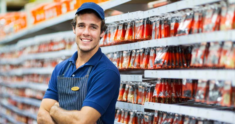 young male casual supermarket worker smiles with arms crossed