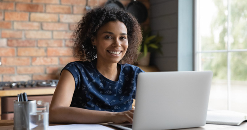 happy remote worker works on her laptop in sunny kitchen