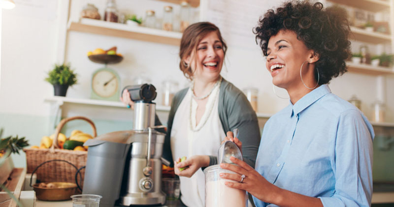 happy coworkers make smoothies together in sunny office kitchen space