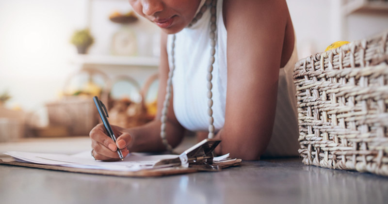 young whole foods shop owner fills out order sheet in kitchen