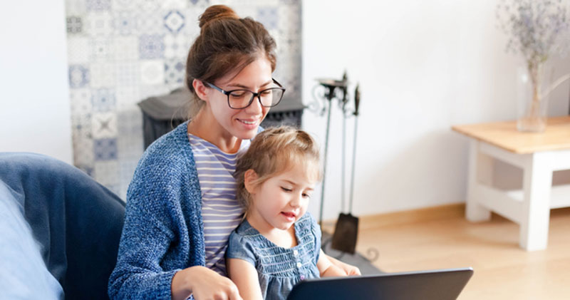 young mother works in home office with infant daughter on her lap