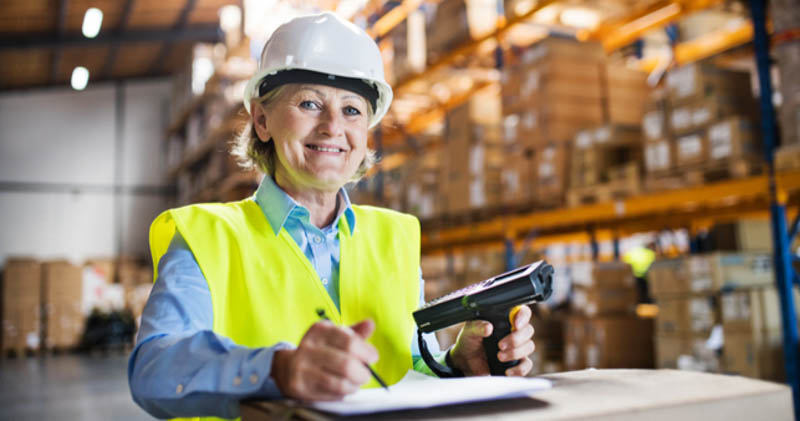 elderly female warehouse worker checks list on clipboard